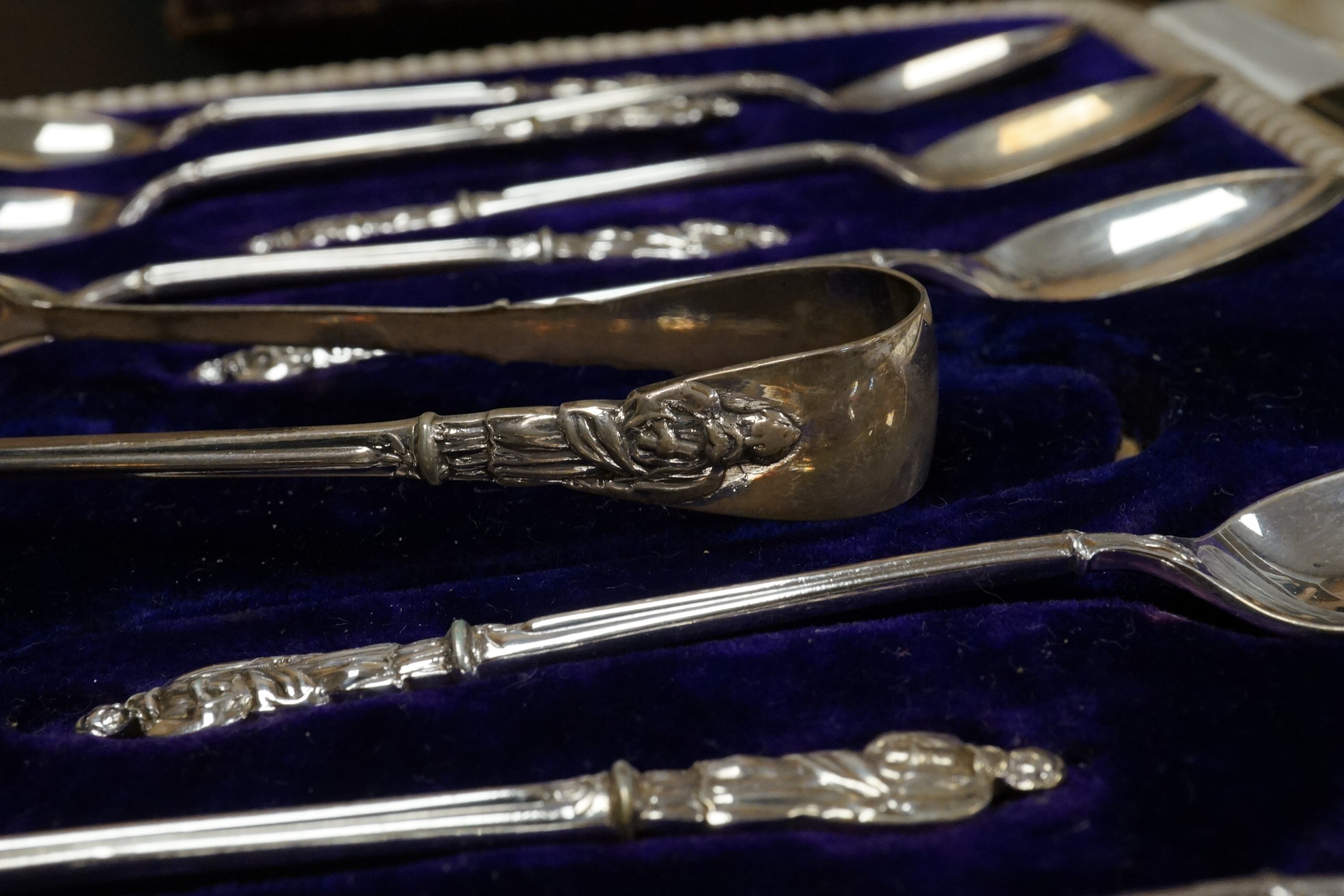 A cased set of twelve Edwardian silver apostle teaspoons with a pair of sugar tongs, Cooper Brothers & Sons, Sheffield, together with a cased Victorian silver bread knife and a cased set of six silver handled steel tea k